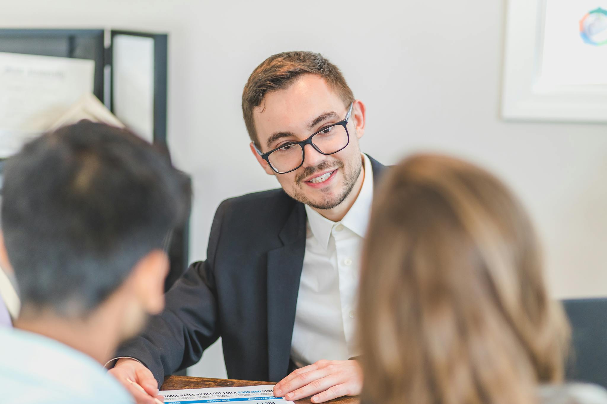 Smiling businessman in a suit and eyeglasses during a team discussion.